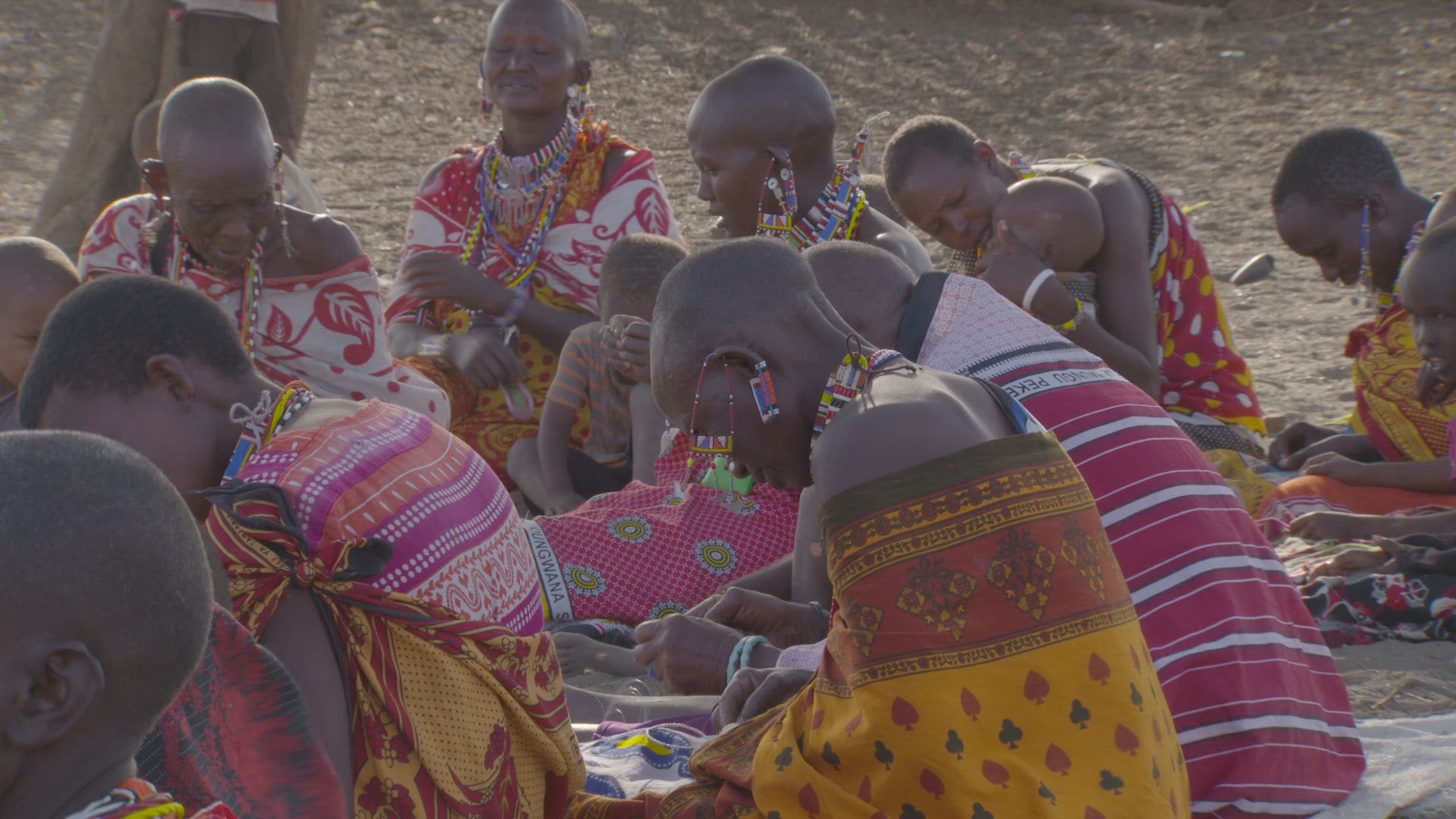 women sitting together making beaded jewelry