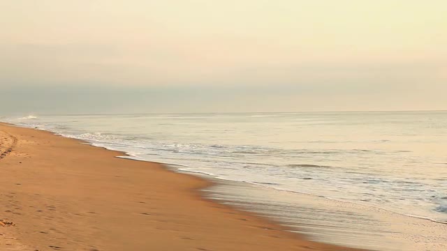 Waves crashing on beach at sunrise