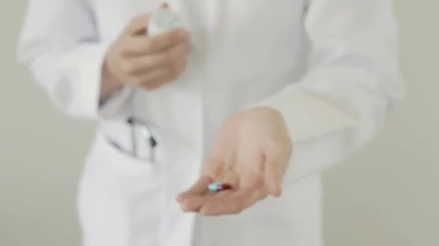 Caucasian doctor pours pills into hand