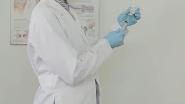 Caucasian doctor prepares an injection, exits frame