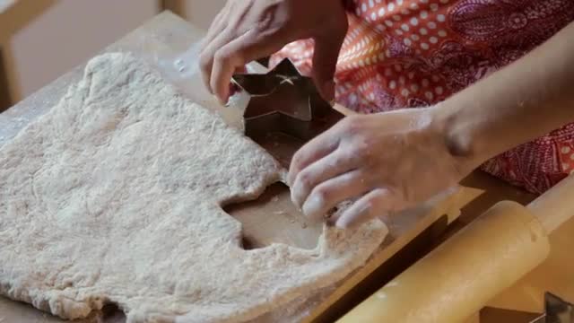 Hispanic woman pressing star shapes in dough