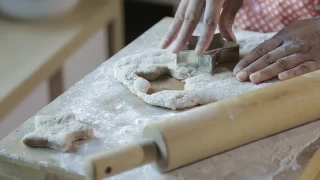 Hispanic woman pressing star shapes in dough