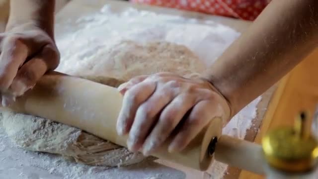 Hispanic woman rolling dough with rolling pin