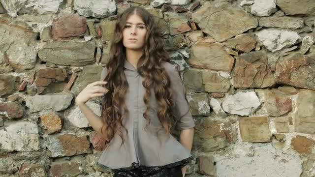 Elegant Fashion Model Poses At Natural Stone Wall In Magic Sun Setting Light