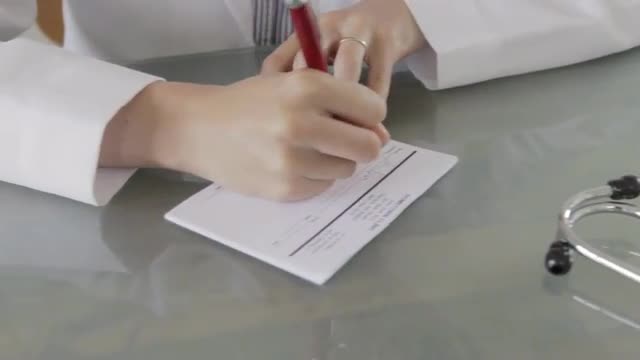 Tracking shot of Caucasian doctor writing prescription