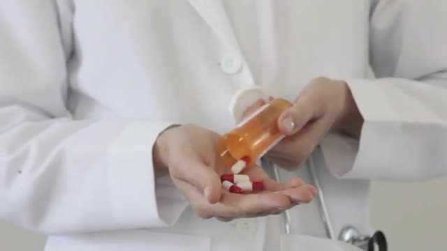 Caucasian doctor pours pills into hand
