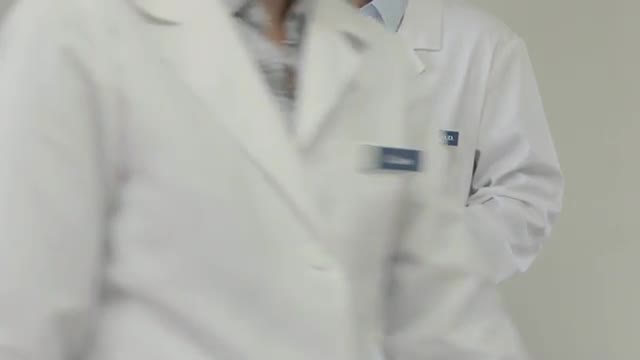 Caucasian nurse crosses frame as doctor is typing on digital tablet