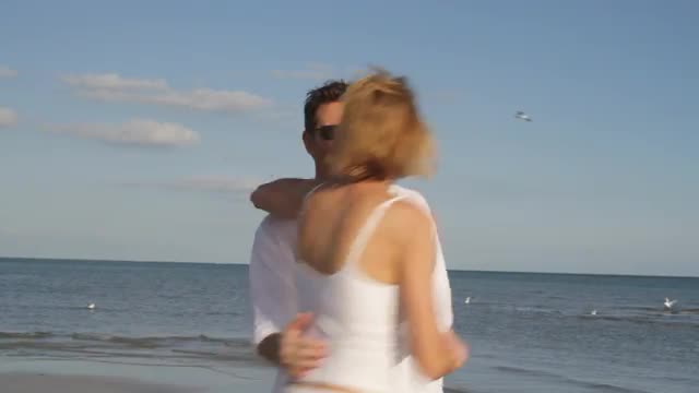 Caucasian woman hugging husband on beach
