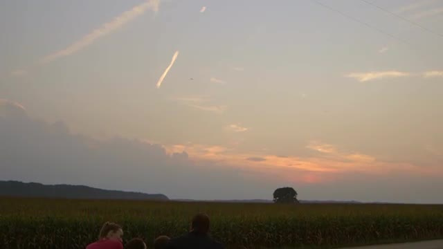 Caucasian watching sunset over crops at dusk