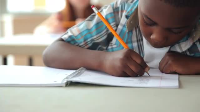 Student writing at desk in classroom