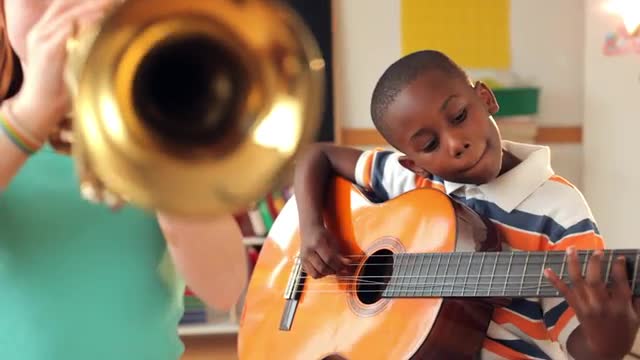 Students playing guitar and trumpet in classroom