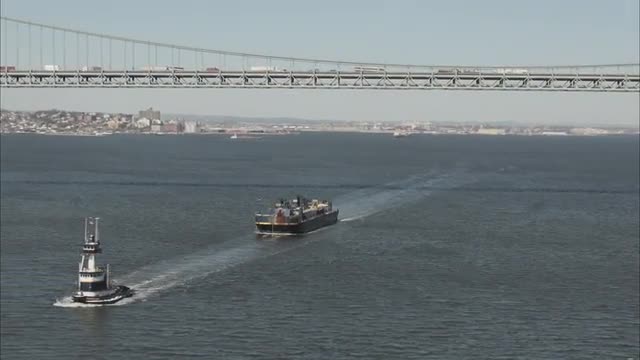AERIAL WIDE view of two ships passing underneath the Verazano Bridge