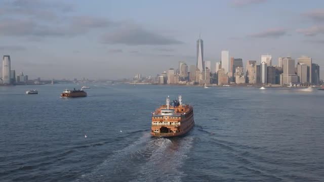 AERIAL WIDE to MEDIUM ORBIT view of Staten Island Ferry with view of Downtown in the background
