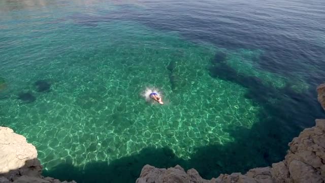 Slow-Mo: Young Muscular Man Jumps Headfirst Into Crystal Clear Blue Water