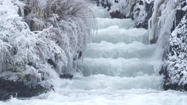 Water flows down some rock steps between frozen grass and trees