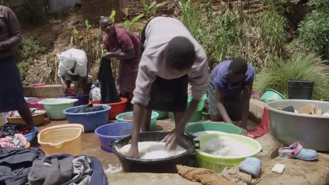 Woman washing clothes and shoes in Kibera Slum, Nairobi.