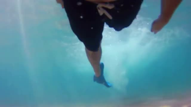 Underwater shot of a diver's legs wearing flippers and swimming near a coral reef