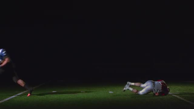 A football player jumps over another who is trying to tackle him