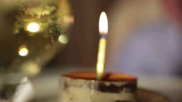 Glass of champagne and candle in the tiramisu cake.