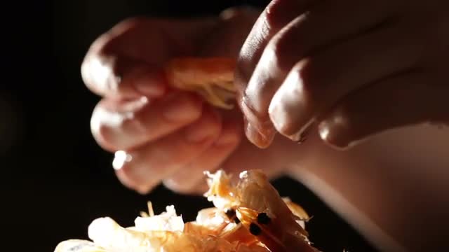 Women's hands are cleaning shrimp.