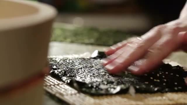 Putting wasabi on the nori while cooking sushi rolls.
