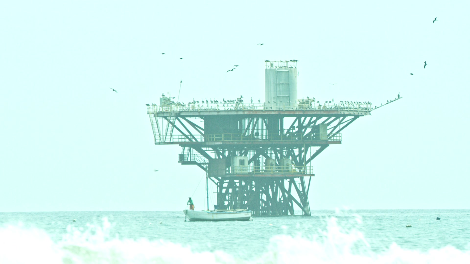 A small fishing boat in front of an offshore oil platform
