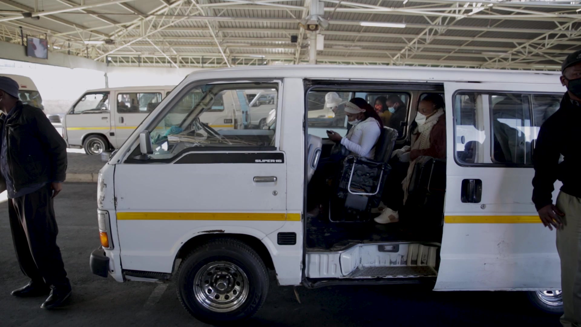 Passengers getting into a taxi wearing face masks