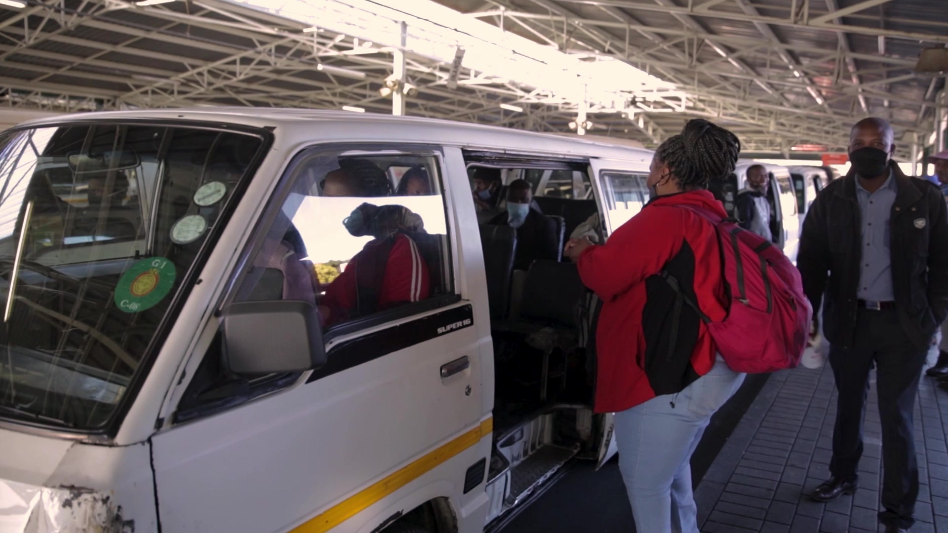 Taxi marshal spraying sanitiser on a passengers hands before getting into the taxi