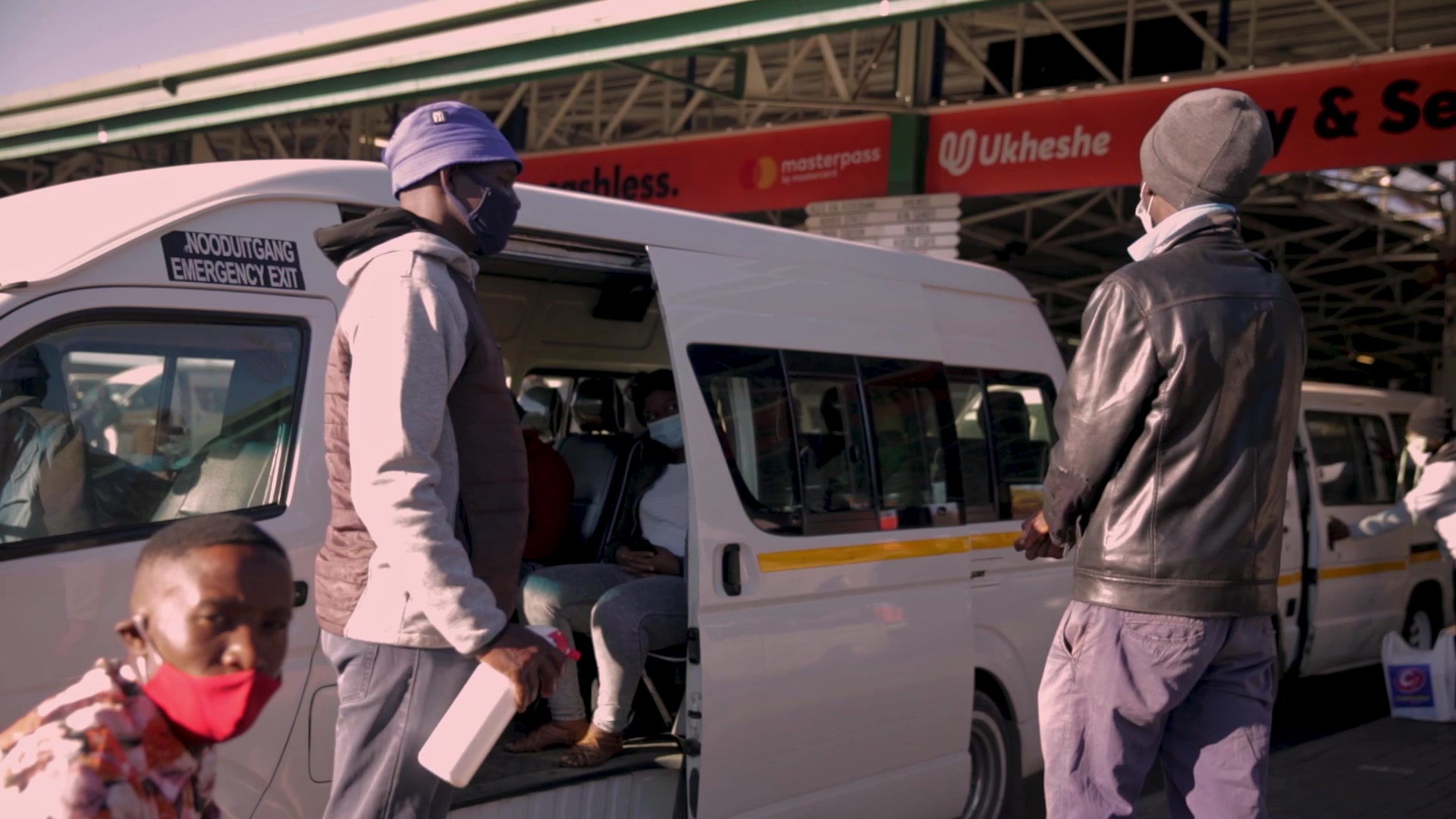 Taxi marshal spraying sanitiser on a passengers hands before getting into the taxi