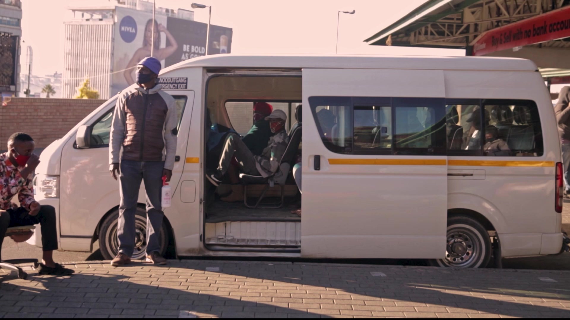 Taxi marshal spraying sanitiser on a passengers hands before getting into the taxi