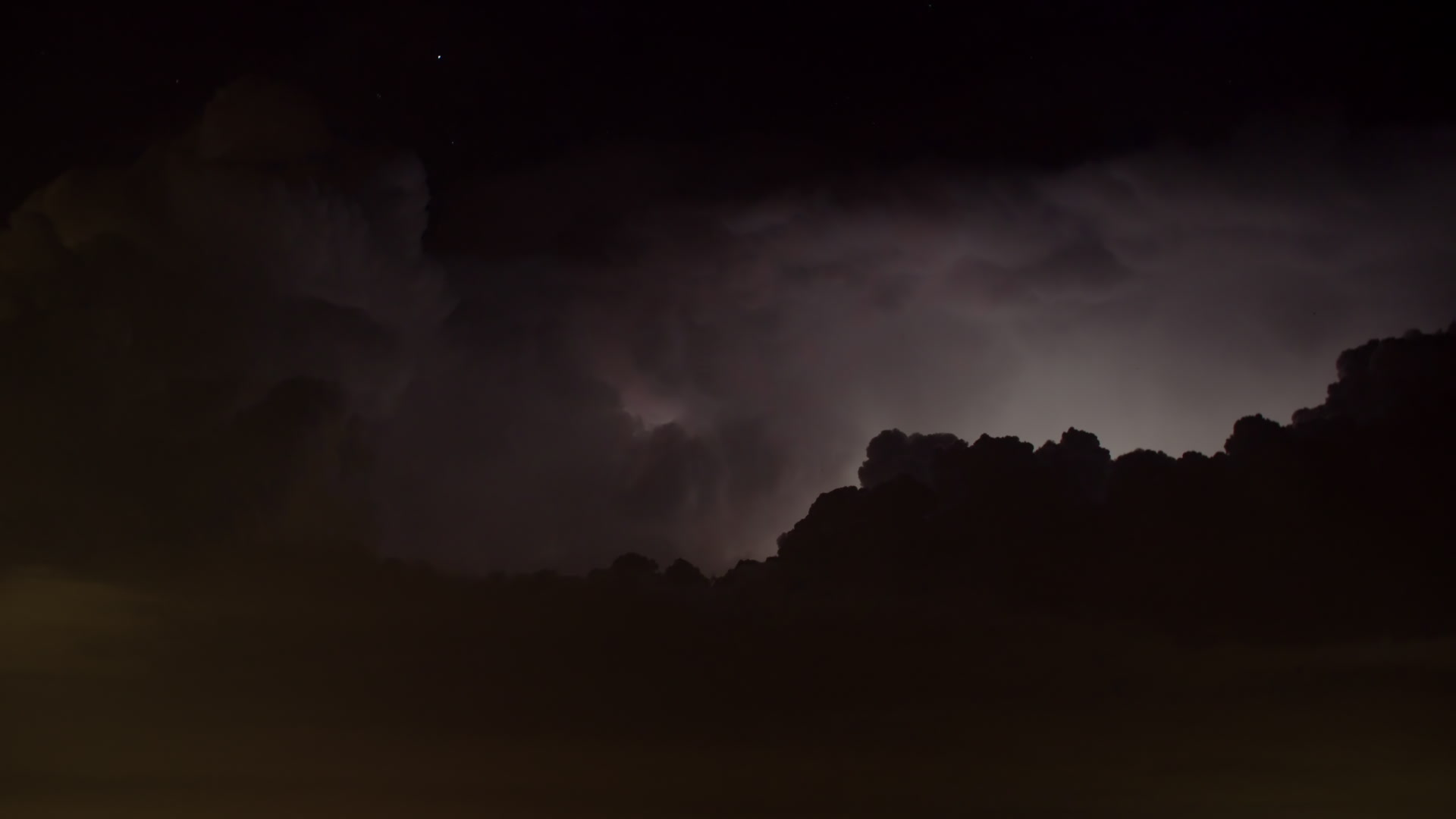 Dramatic, continuous lightning flashes at top of storm, night