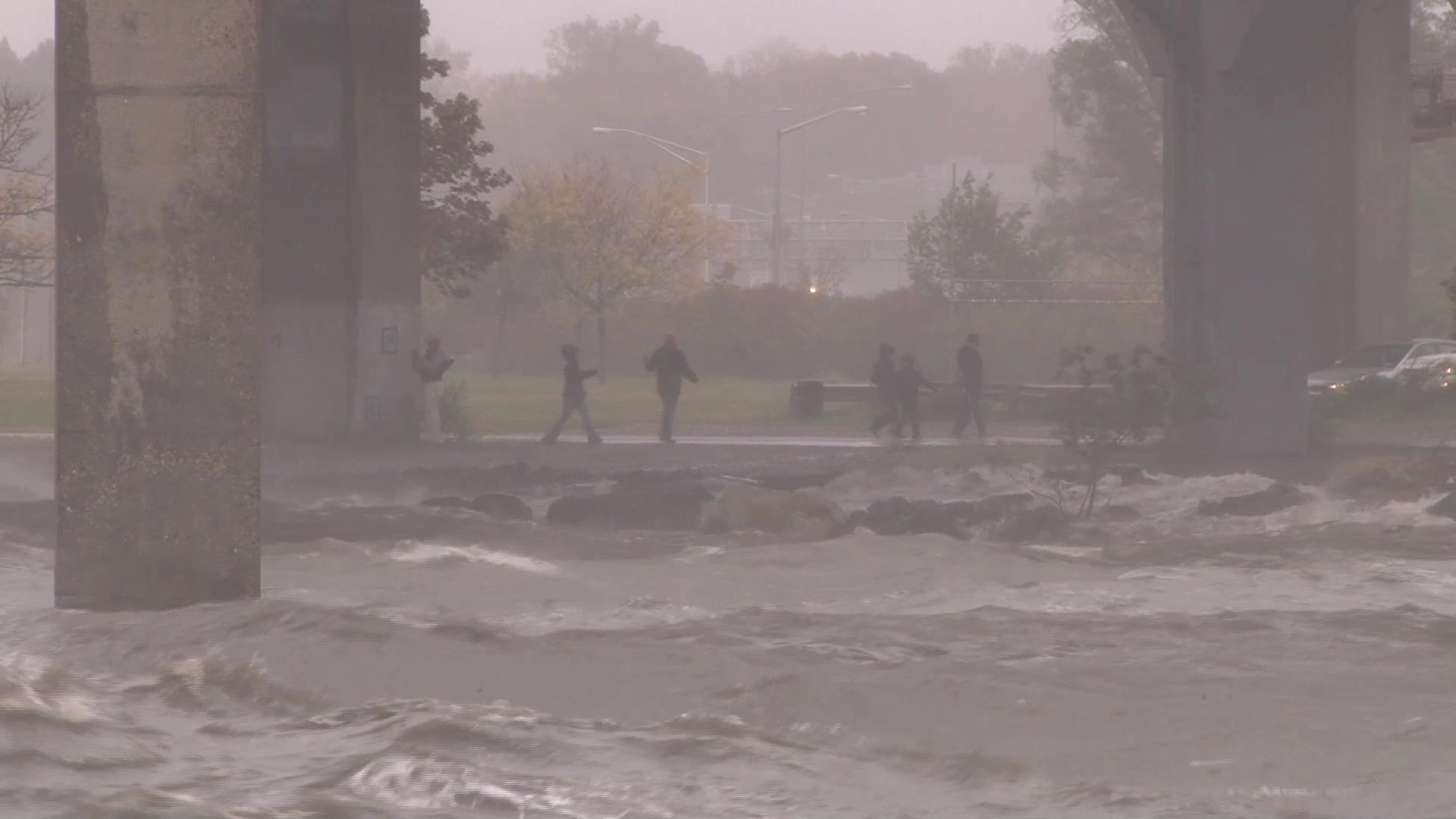Hurricane Sandy - People hang out by crashing waves beneath bridge