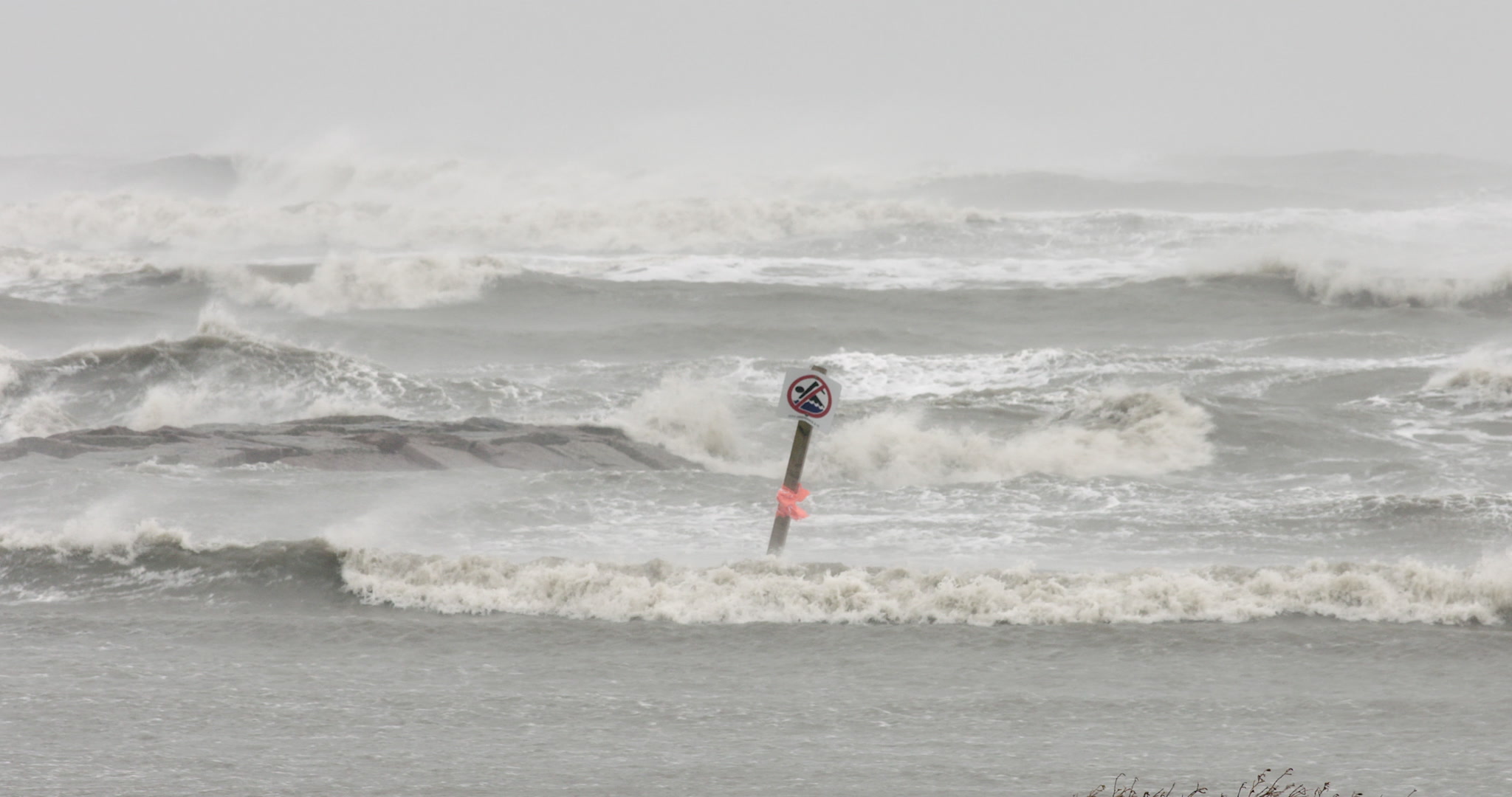 Hurricane Delta - Waves crash by no swimming sign