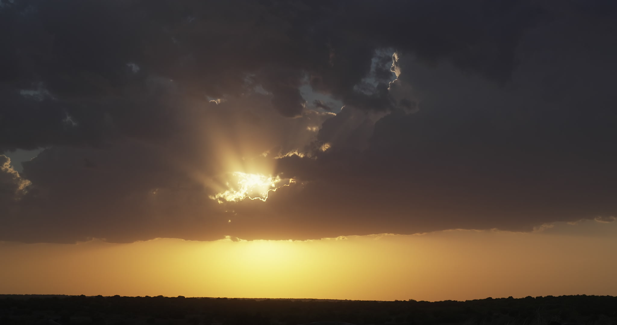 4K Storm Clouds - Beautiful orange and gold sun rays pierce storm at sunset