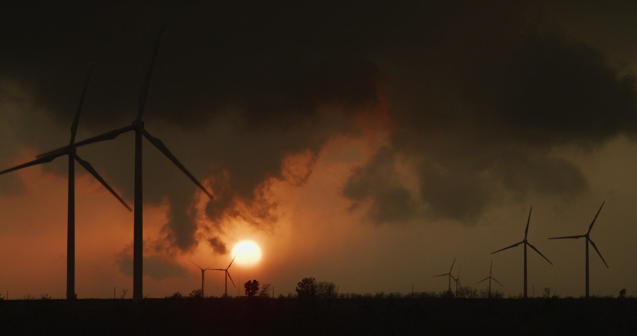 Storm clouds clear over sunset and wind farm, 4K