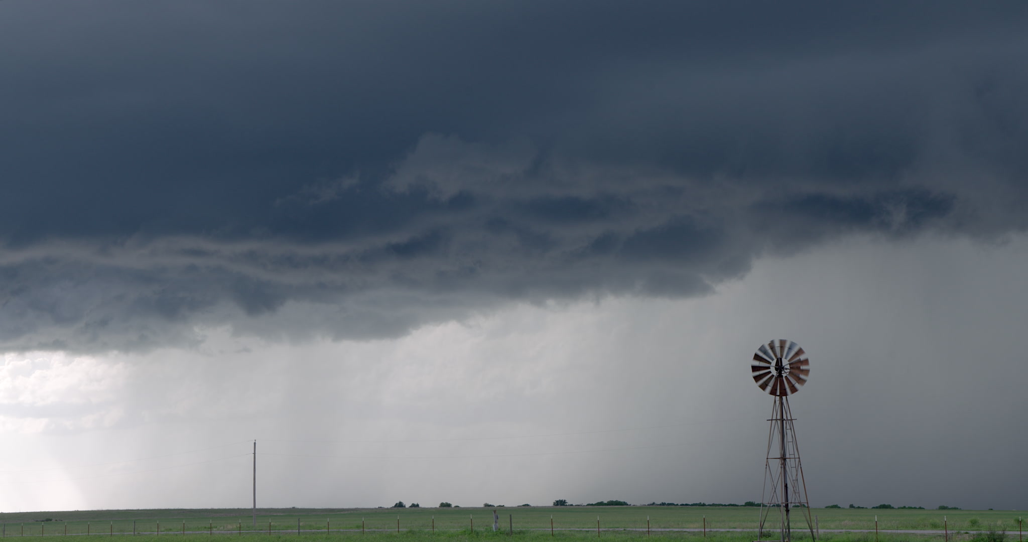 Storm clouds drift over spinning windmill, 4K