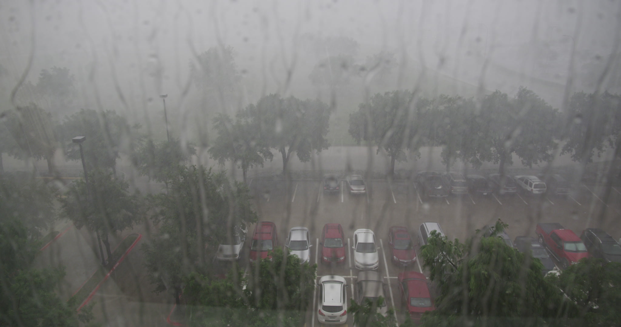 Rain storm - Rain drops on window, cars, parking lot below, 4K