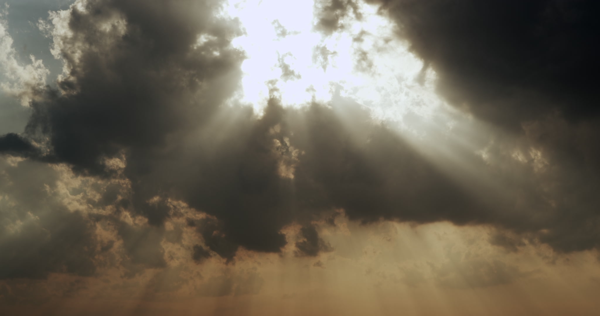Bright golden shafts of sun light stream down through dark clouds, 4K