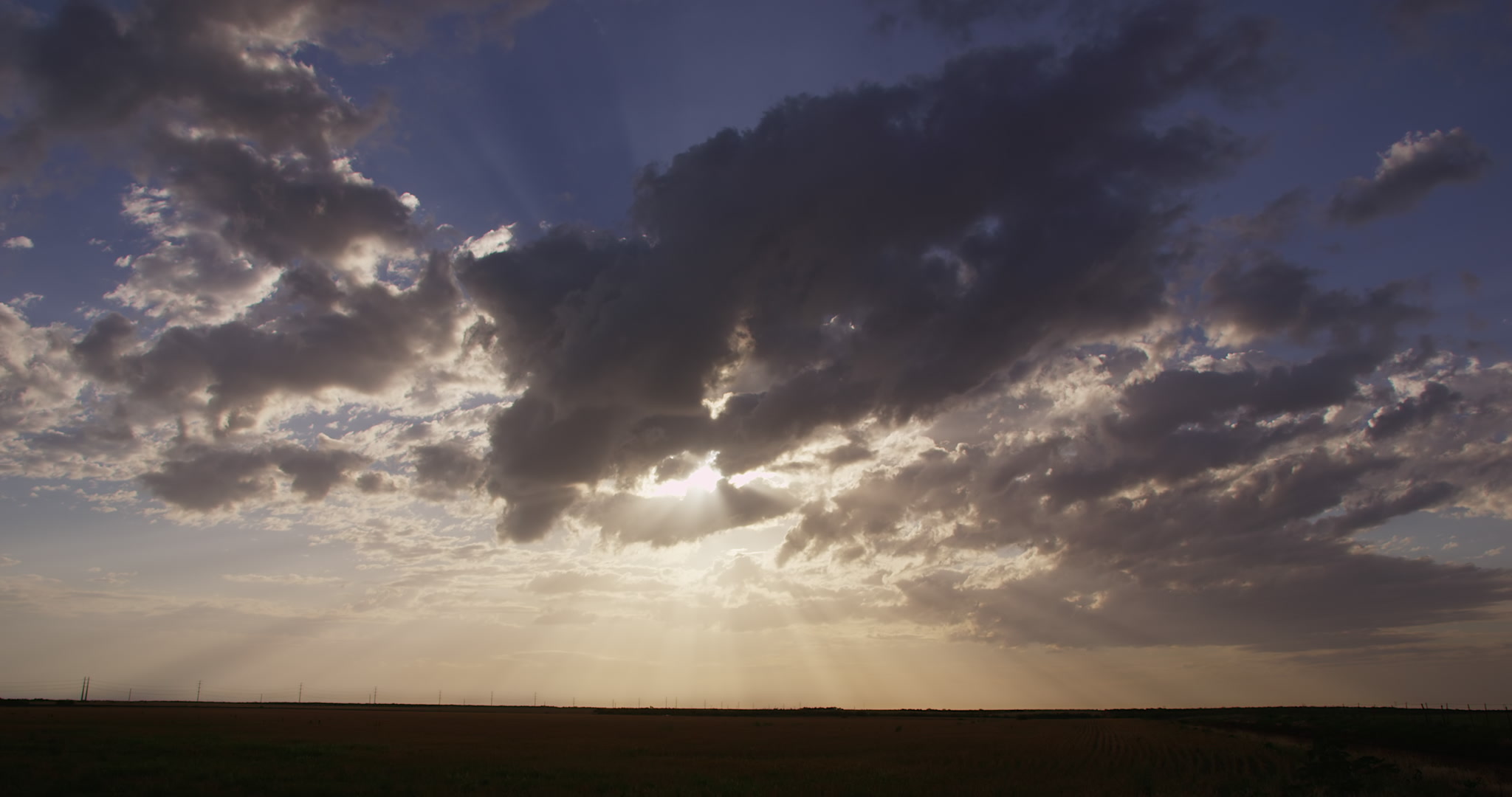 Large, golden sun beams stream down from clouds, late day, Texas, 4K