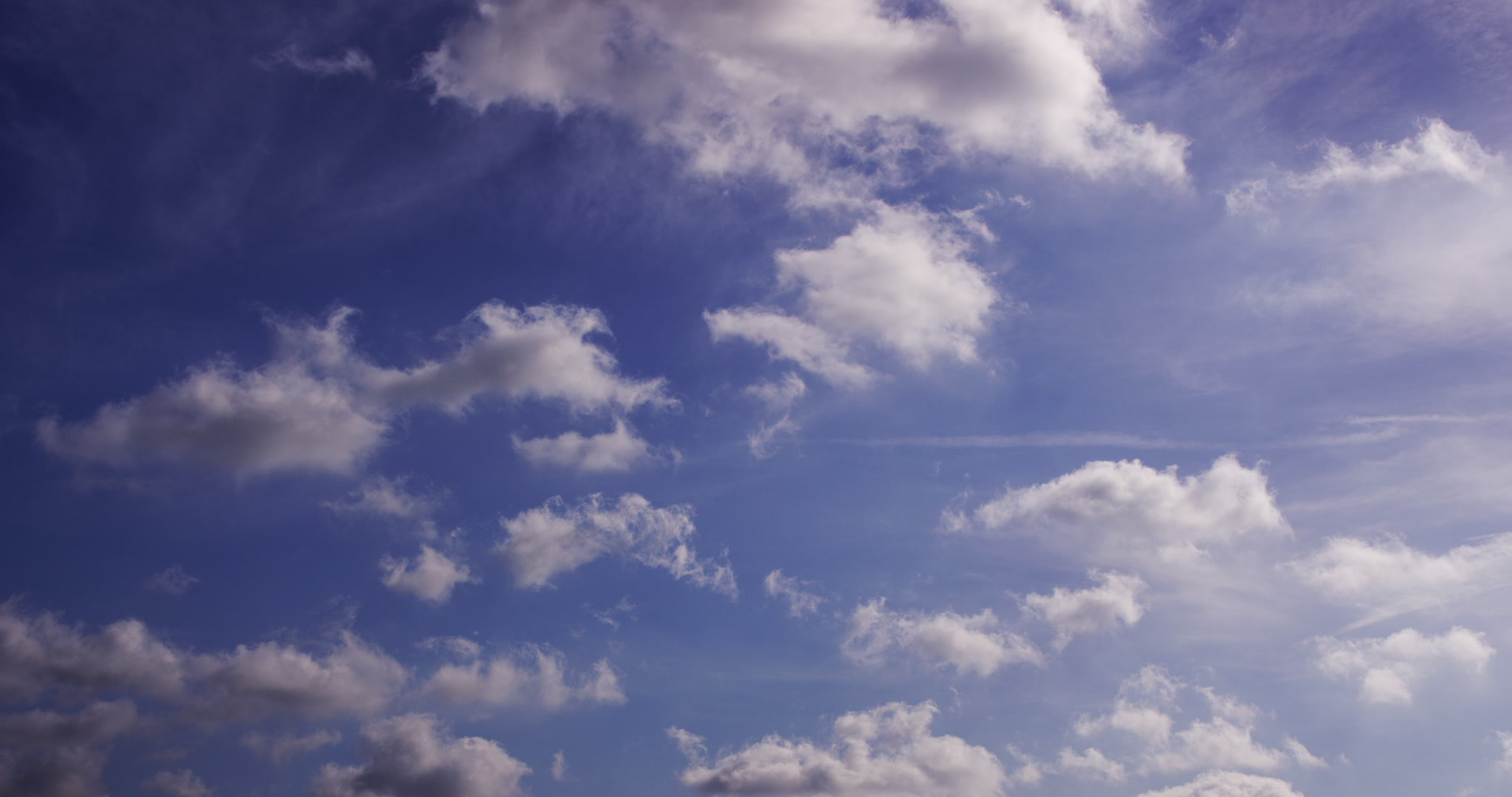 Small stratus clouds drift quickly across blue sky, 4K