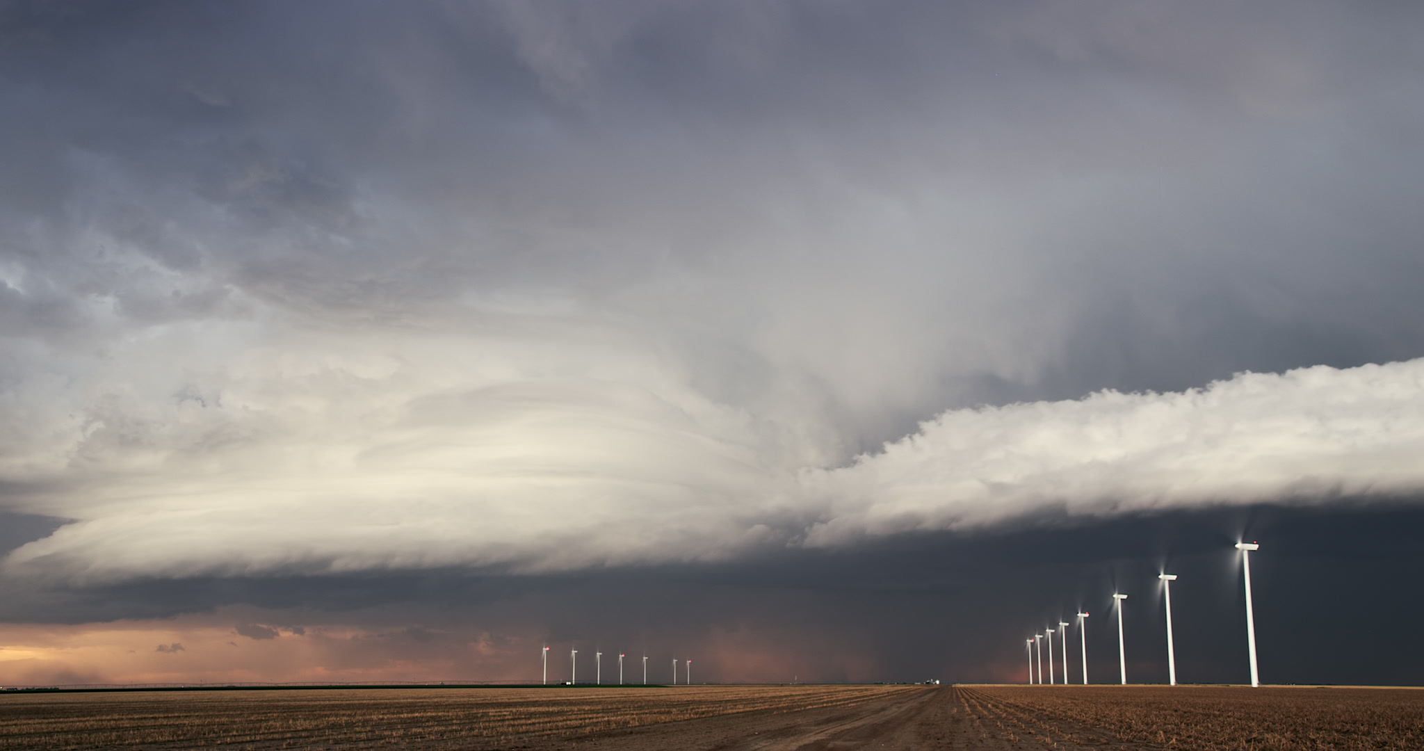 Unique, wide-angle shot of severe supercell thunderstorm drifting over wind farm, 4K