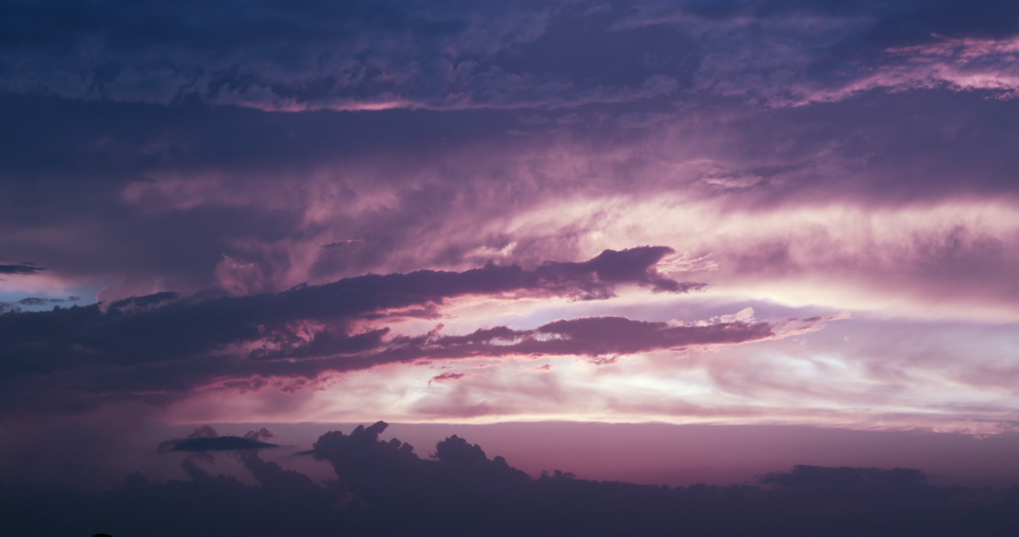 Beautiful blue and orange storm clouds drift over setting sun, 4K