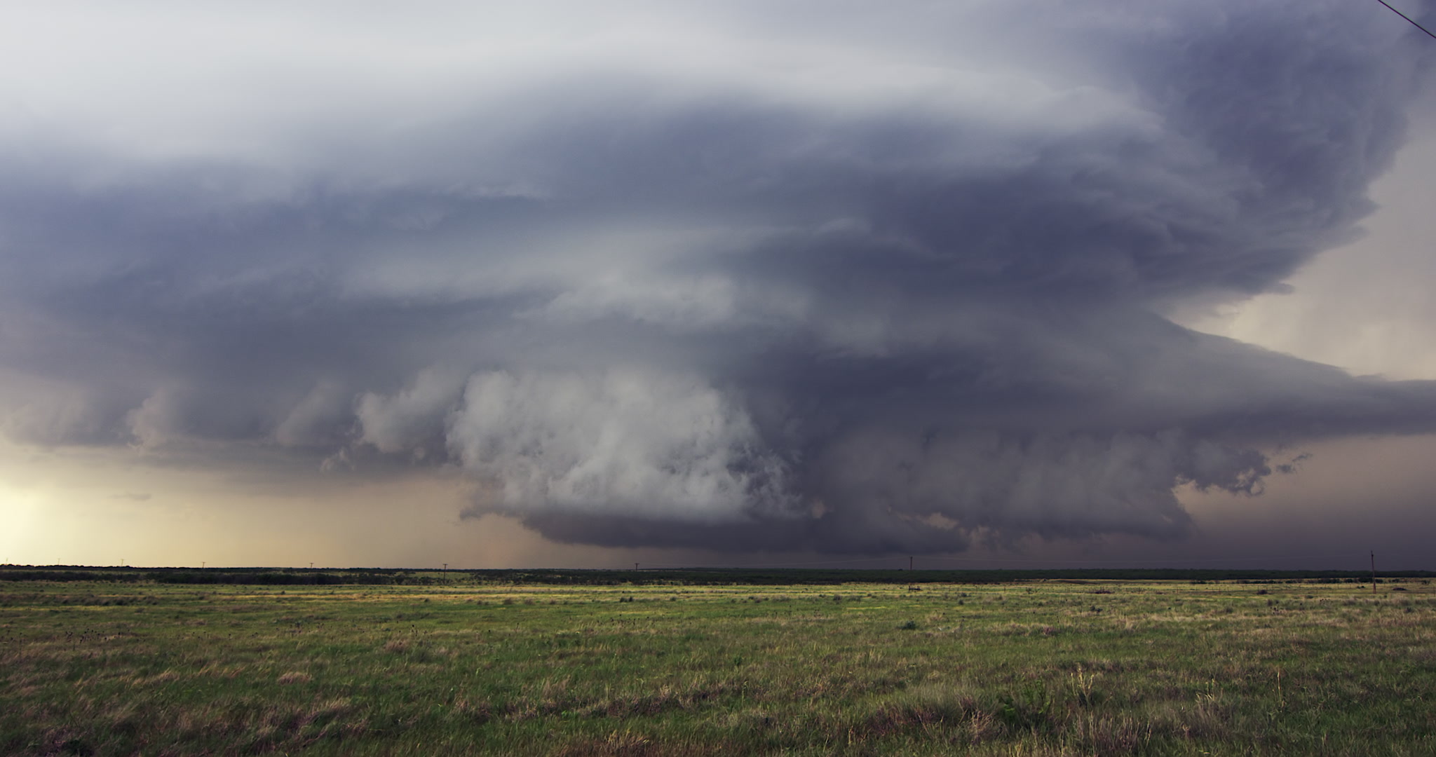Severe, rotating supercell thunderstorm spins over green prairie, evening, Texas, 4K