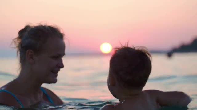 Mother and son having fun in sea at sunset