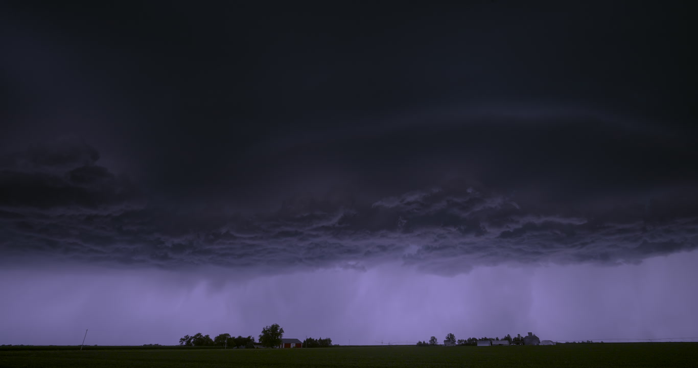 Night view of alien-like storm drifting over two farms, 4K