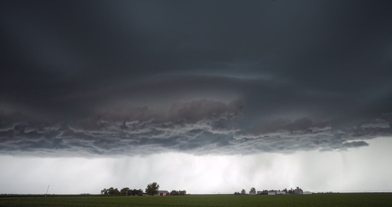 Scary alien-like storm drifts over two farms, late day, 4K