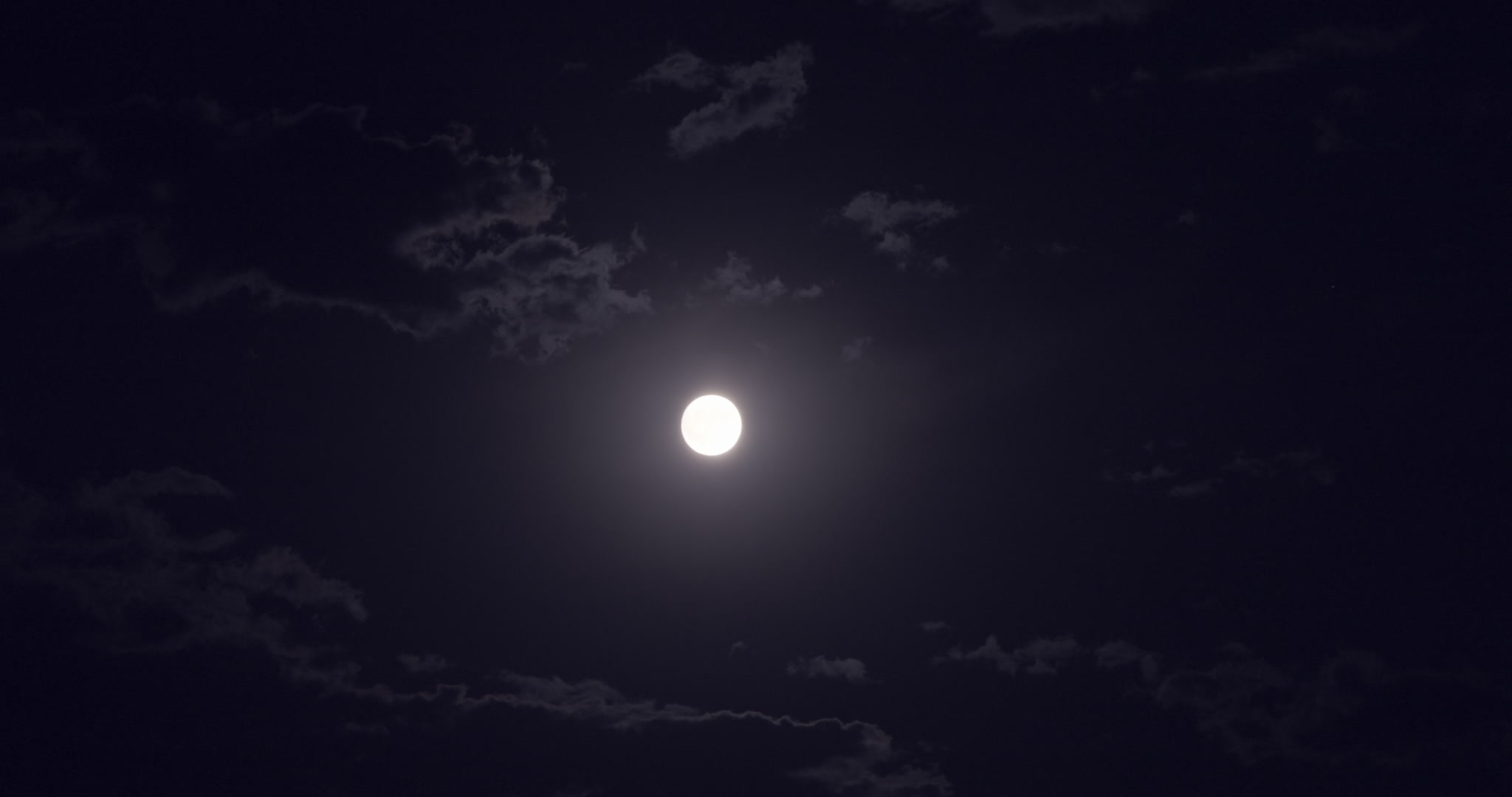 Bright, yellow full moon in dark sky with clouds drifting by, 4K