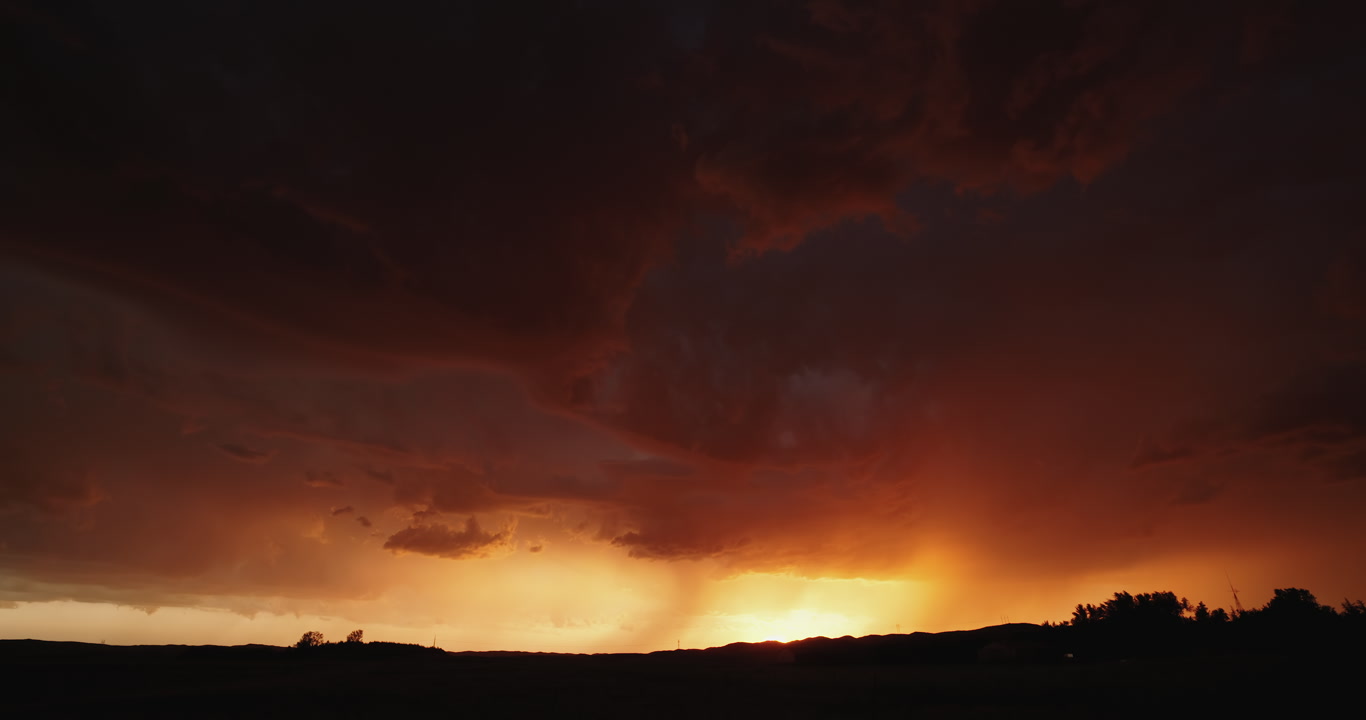 Long-duration shot of stormy sky lit orange by setting sun, Nebraska sandhills, 4K
