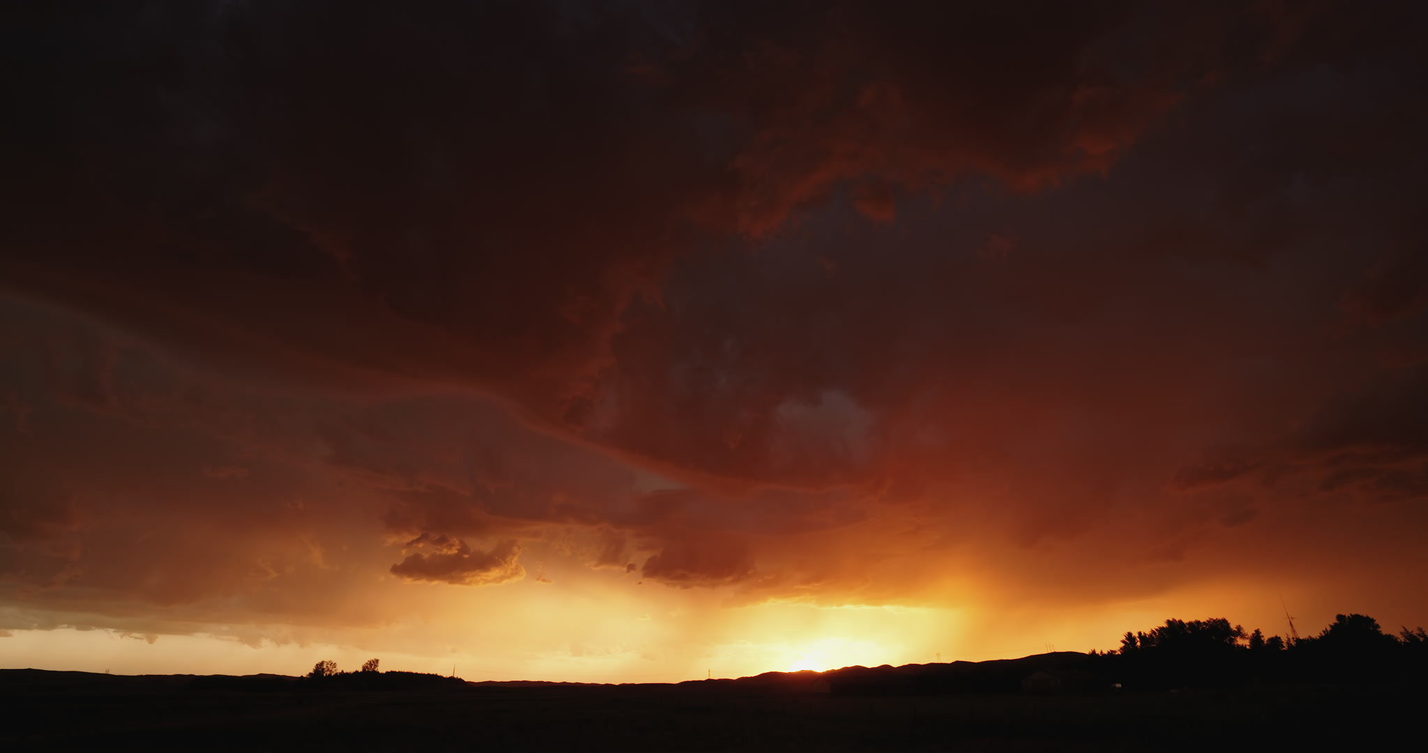 Long-duration shot of stormy sky lit orange by setting sun, Nebraska sandhills, 4K