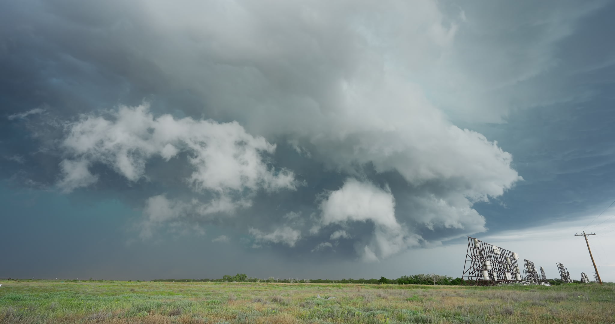 Large severe storm drifts over prairie and wind machines, 4K